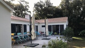 Eine Terrasse im Freien mit einer Ziegeldachdeckung, Sitzgelegenheiten und einem Gartenbereich.