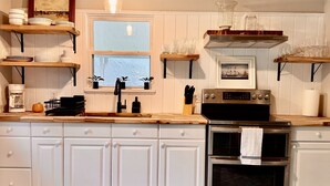 A kitchen with wooden cabinets, a stove, and a window. - Cozy cottage located in the heart of the Mayport fishing village. Pool & Patio! (Jacksonville)