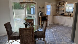 A dining area with wicker chairs, a glass table, and a chandelier. - Cozy cottage located in the heart of the Mayport fishing village. Pool & Patio! (Jacksonville)