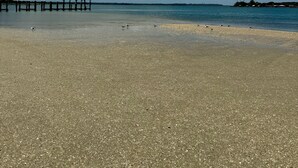 A beach with pebbles, a wooden pier, and a clear blue sky. - Cozy cottage located in the heart of the Mayport fishing village. Pool & Patio! (Jacksonville)