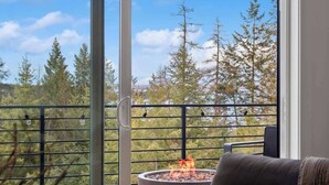 A balcony with a fire pit, a view of trees, and a clear sky. - Lake Views | Modern & Luxurious | Walk to Town (Lakeside)