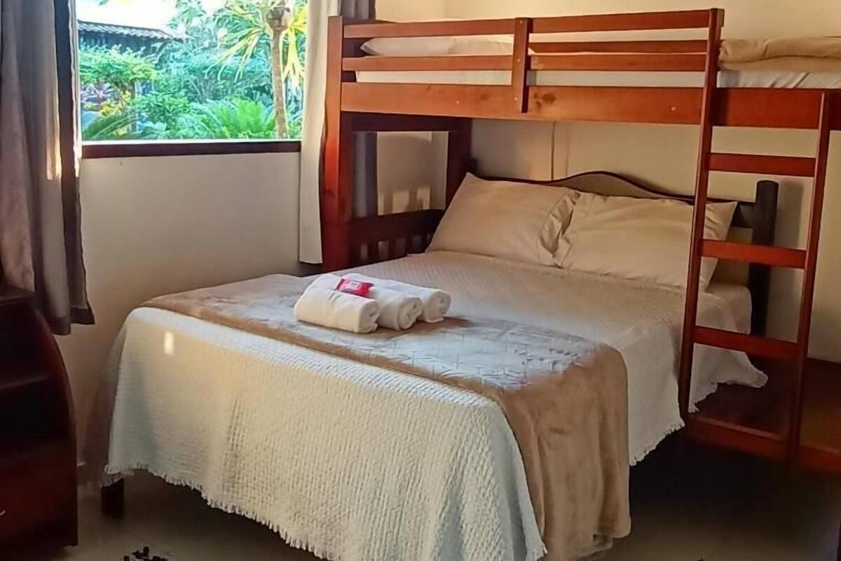 A bunk bed room with a window, curtains, and an air conditioning unit.