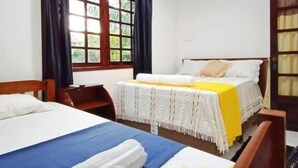 Ein Hotelzimmer mit zwei Betten, einem Holzkopfstück, einem Fenster mit Vorhängen und einer Tür mit Glasfeld.