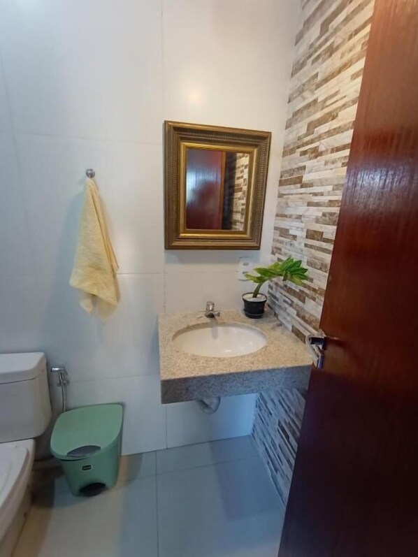 A bathroom with a sink, mirror, and toilet. - Legatum (Campos)