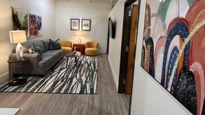 A modern hallway with a grey sofa, a patterned rug, and abstract wall art.