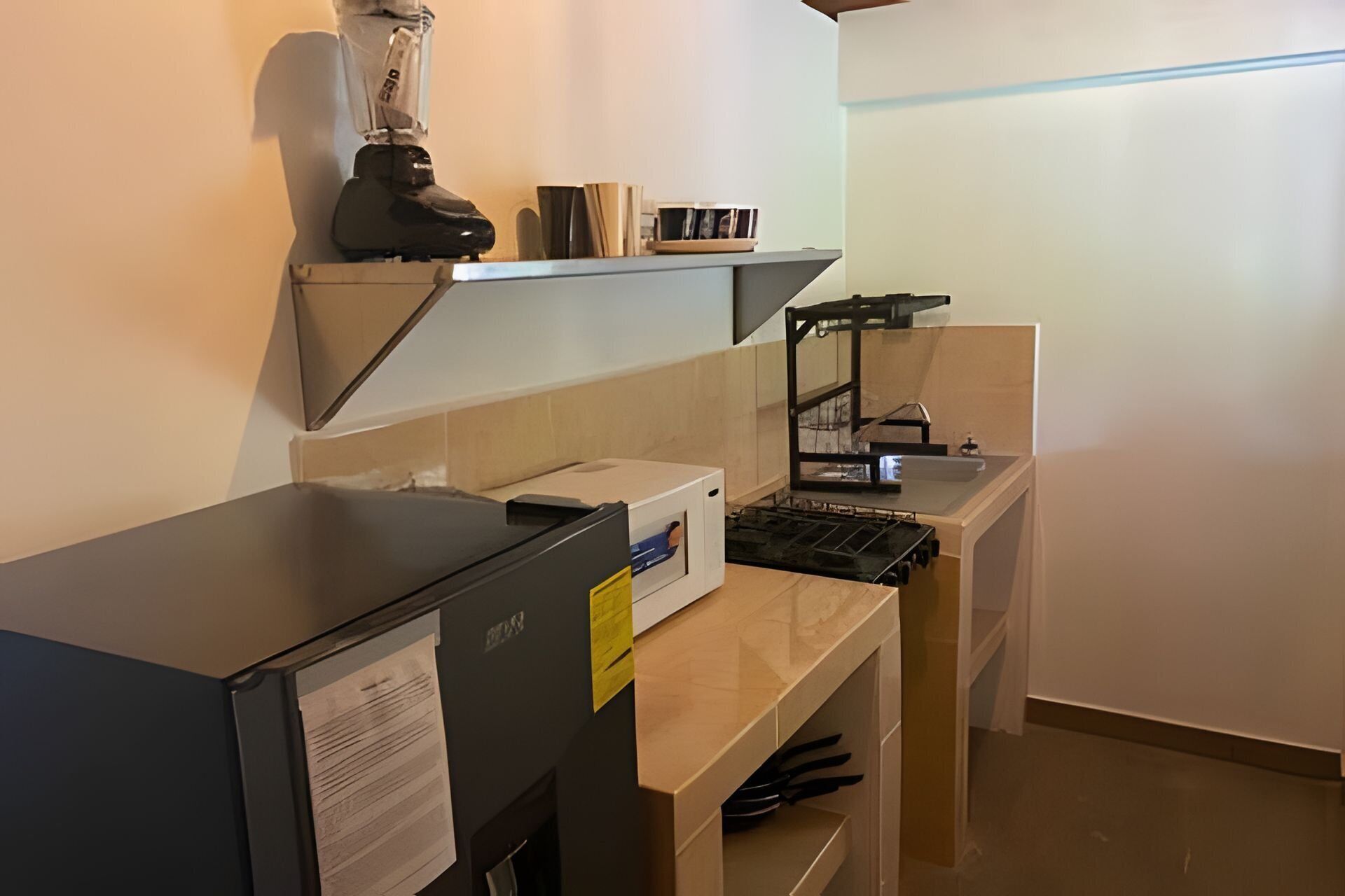 A kitchen with a black countertop, a blender, a sink, and a small shelf with items.