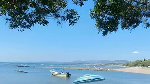 Uma praia com barco, guarda-sol e terreno rochoso.