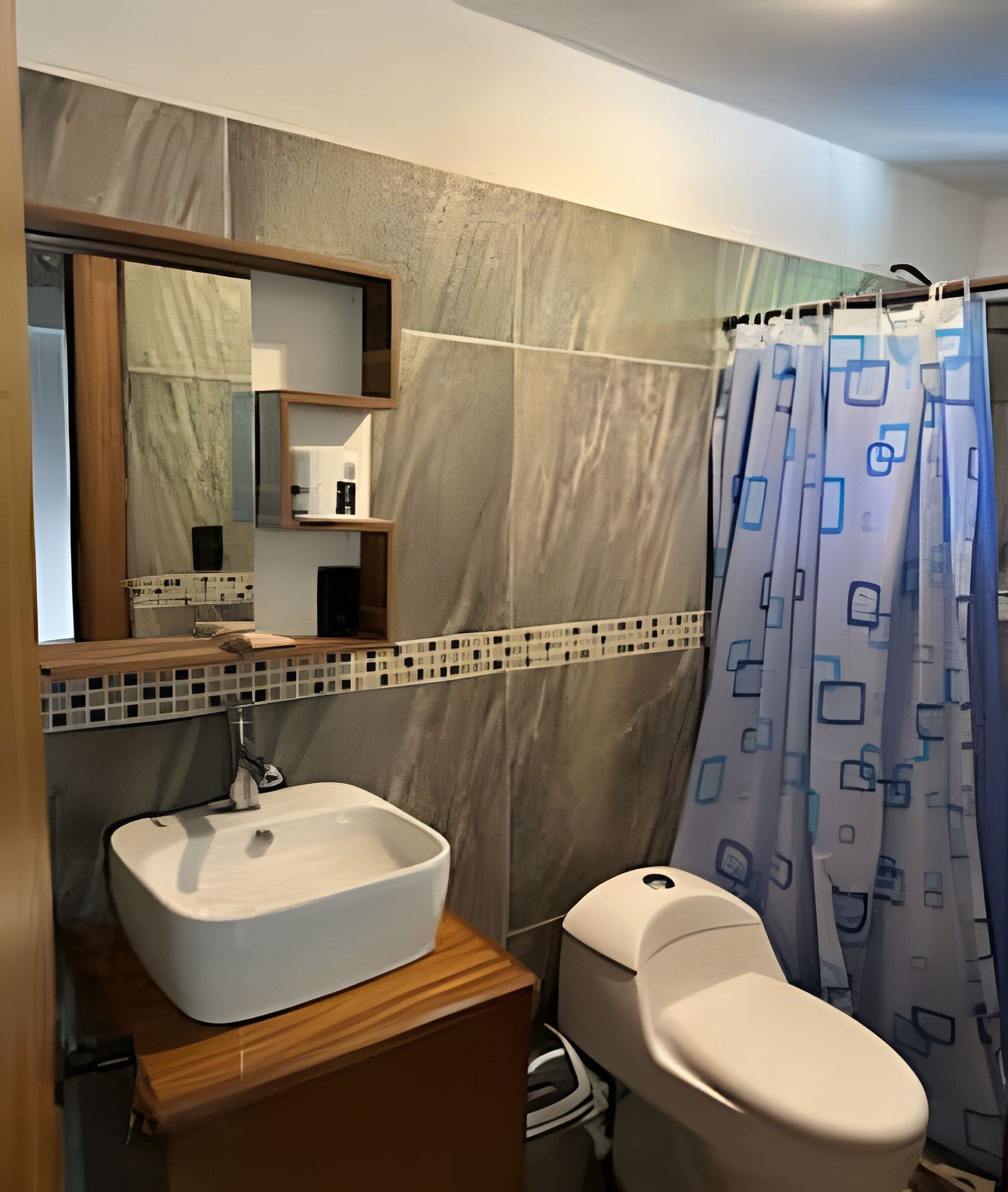 A bathroom with a white sink, a toilet, and a shower curtain with a geometric pattern.