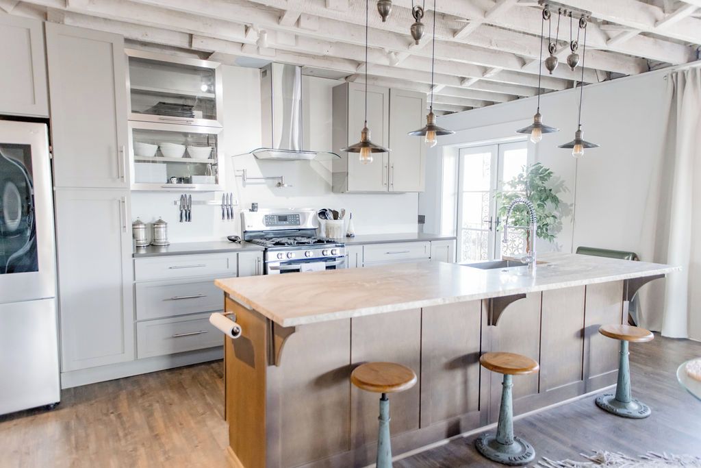 A kitchen with a central island, bar stools, and pendant lighting.