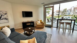 A modern living room with a sofa, coffee table, and a TV mounted on the wall. - Clean, bright, with large exclusive patio, parking, close to airport and beach (San Diego)