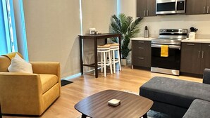 A modern living room with a sofa, a coffee table, and a kitchen area with a microwave and stove. - Clean, bright, with large exclusive patio, parking, close to airport and beach (San Diego)
