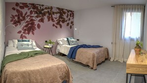 Une chambre d’hôtel avec deux lits, une petite table et une fresque murale.