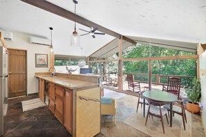 Une cuisine dotée d’un grand îlot central, d’un coin repas avec une table et des chaises, et offrant une vue sur l’extérieur.