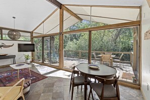 Una habitación amplia con ventanas grandes, una mesa de comedor, sillas, un televisor y una alfombra.