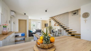Eine moderne Küche mit einer Holzausziehtheke, einer Obstschale und einer Treppe, die in einen Essbereich führt.
