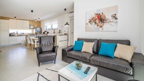 Ein stilvolles Wohnzimmer mit einem grauen Sofa, einem Couchtisch und einer Fernbedienung.
