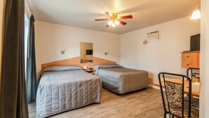 A room with two beds, a ceiling fan, a wooden table, and a chair. - Motel Park (Val-d'Or)