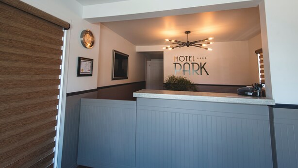 A reception area with a sign that reads "Motel Park" and a modern chandelier. - Motel Park (Val-d'Or)
