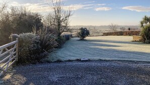 A gravel path leading to a rural property with a wooden gate, sparse vegetation, and a distant view of a field. - 2 bedroom accommodation in Aldeby, near Beccles (Aldeby, near Beccles)