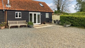 A house with a tiled roof, a front door, a bench, and potted plants. - 2 bedroom accommodation in Aldeby, near Beccles (Aldeby, near Beccles)