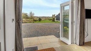 An open door leading to a gravel driveway, a wooden gate, and a view of a rural landscape. - 2 bedroom accommodation in Aldeby, near Beccles (Aldeby, near Beccles)