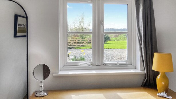 A room with a window, a wooden desk, a mirror, and a lamp. - 2 bedroom accommodation in Aldeby, near Beccles (Aldeby, near Beccles)