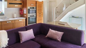 A modern kitchen with wooden cabinets, a built-in oven, and a glass dining table. - 2 bedroom accommodation in Aldeby, near Beccles (Aldeby, near Beccles)