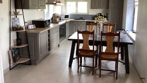 A modern kitchen with grey cabinets, a dining table with chairs, and a window providing natural light.