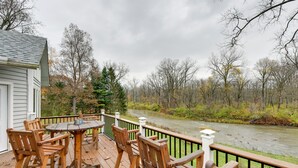 Eine Holzterrasse mit Tisch und Stühlen mit Blick auf einen Fluss.