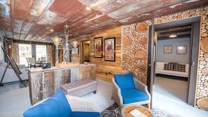 Ein rustikaler Innenraum mit Holzbalkendecke, einer Bar und Sitzgelegenheiten mit blauen Kissen.
