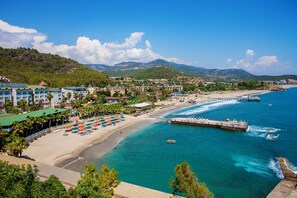 Ein Küstenort mit Strand, einer Mole und einem Bergpanorama.