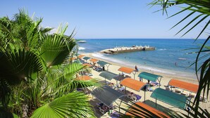 A beach with umbrellas and lounge chairs, a pier, and clear blue water. - Seven Seas Palmeras Bay (Alanya)