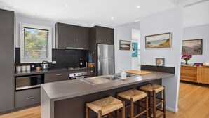 A modern kitchen with dark cabinetry, stainless steel appliances, and a central island with bar stools.
