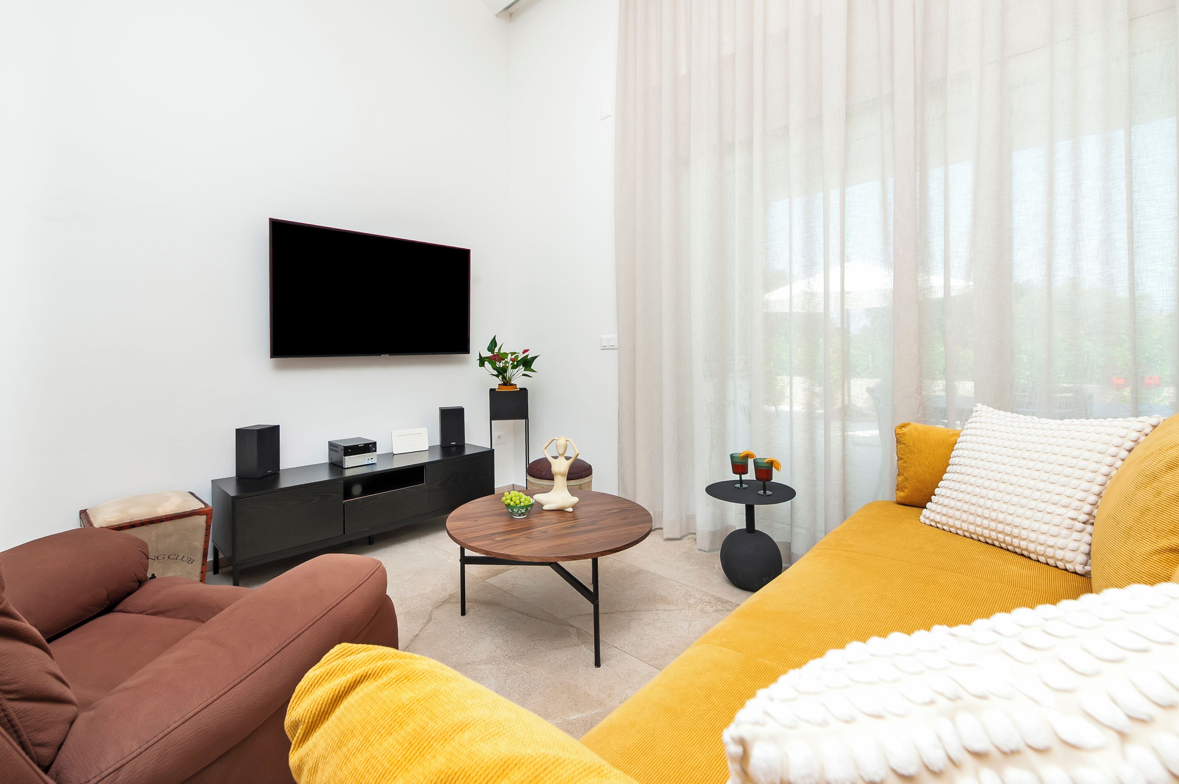 Un salon moderne avec un téléviseur à écran plat, un canapé, une table basse et une petite table d’appoint avec des boissons.