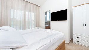 A modern hotel room with a large bed, a TV mounted on the wall, and a wardrobe. - Echo villa, Istra, pool/jacuzzi, BBQ, pet friendly (Šegotići)