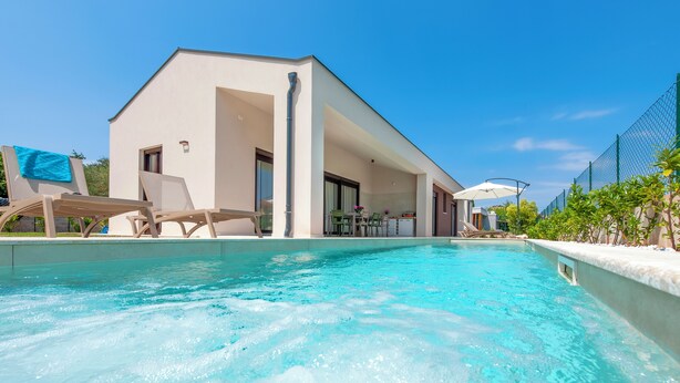 A modern poolside area with a clear pool, lounge chairs, and a building with large windows. - Echo villa, Istra, pool/jacuzzi, BBQ, pet friendly (Šegotići)