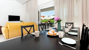 A modern dining area with a black table set for breakfast, yellow sofa, and a TV mounted on the wall. - Echo villa, Istra, pool/jacuzzi, BBQ, pet friendly (Šegotići)