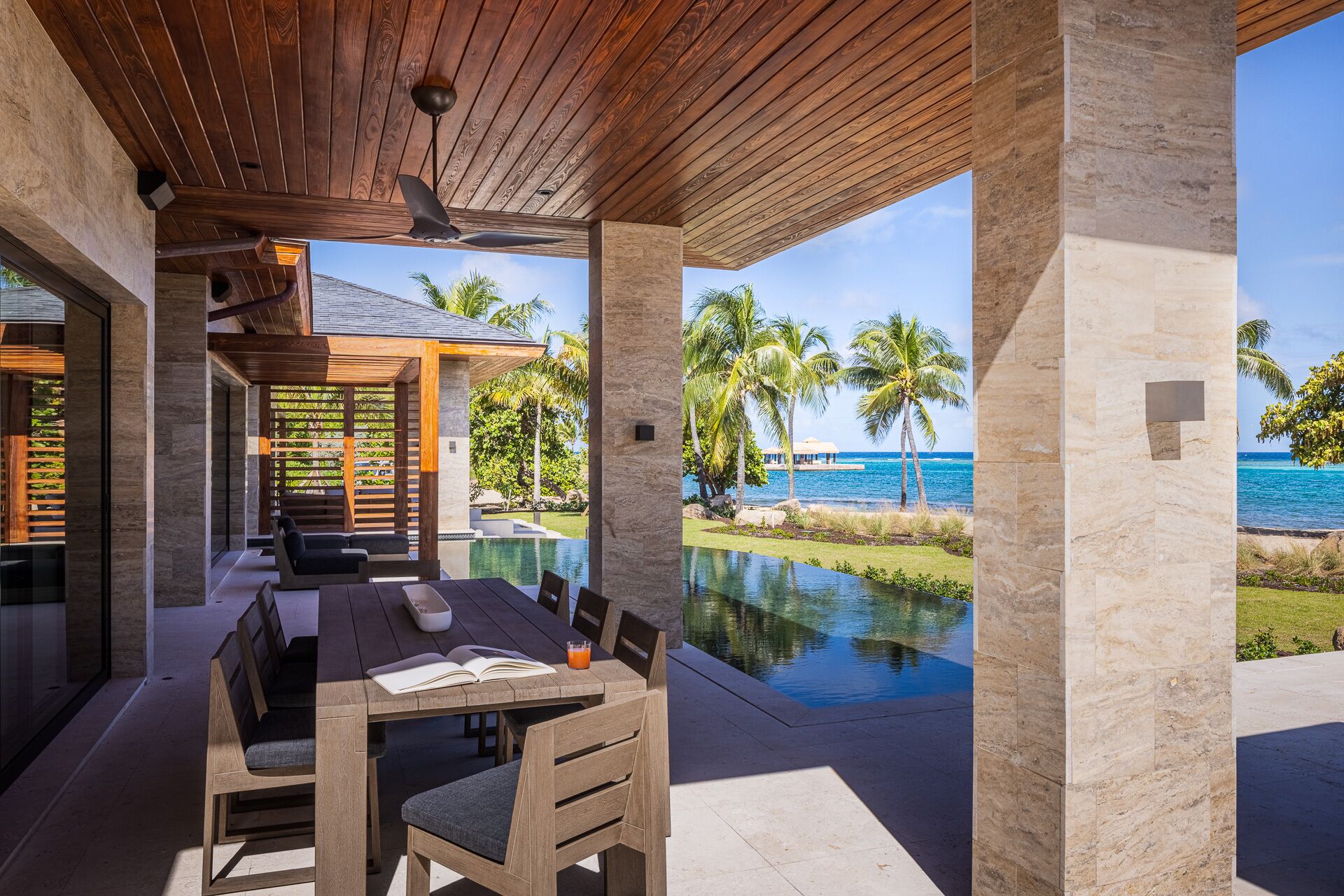 A covered outdoor dining area with a view of a pool and ocean.
