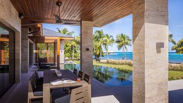 A covered outdoor dining area with a view of a pool and ocean.