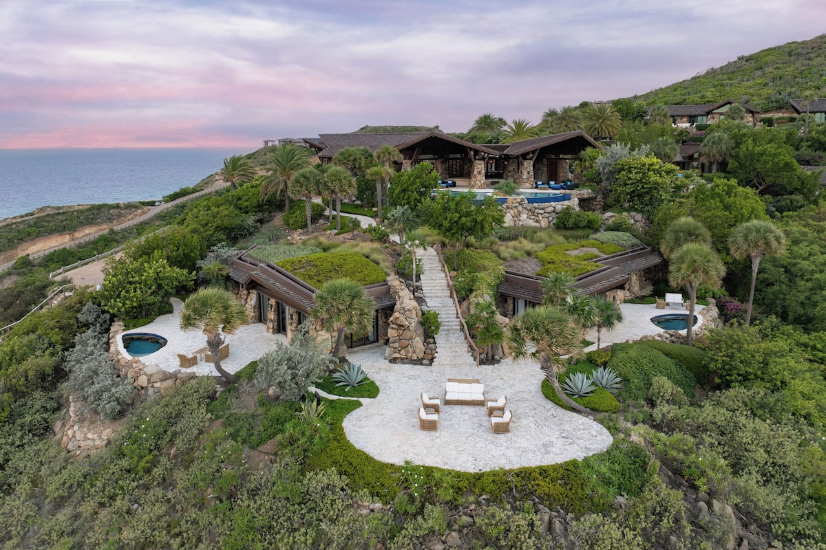A luxurious resort with multiple pools, a central patio, and a scenic ocean view.