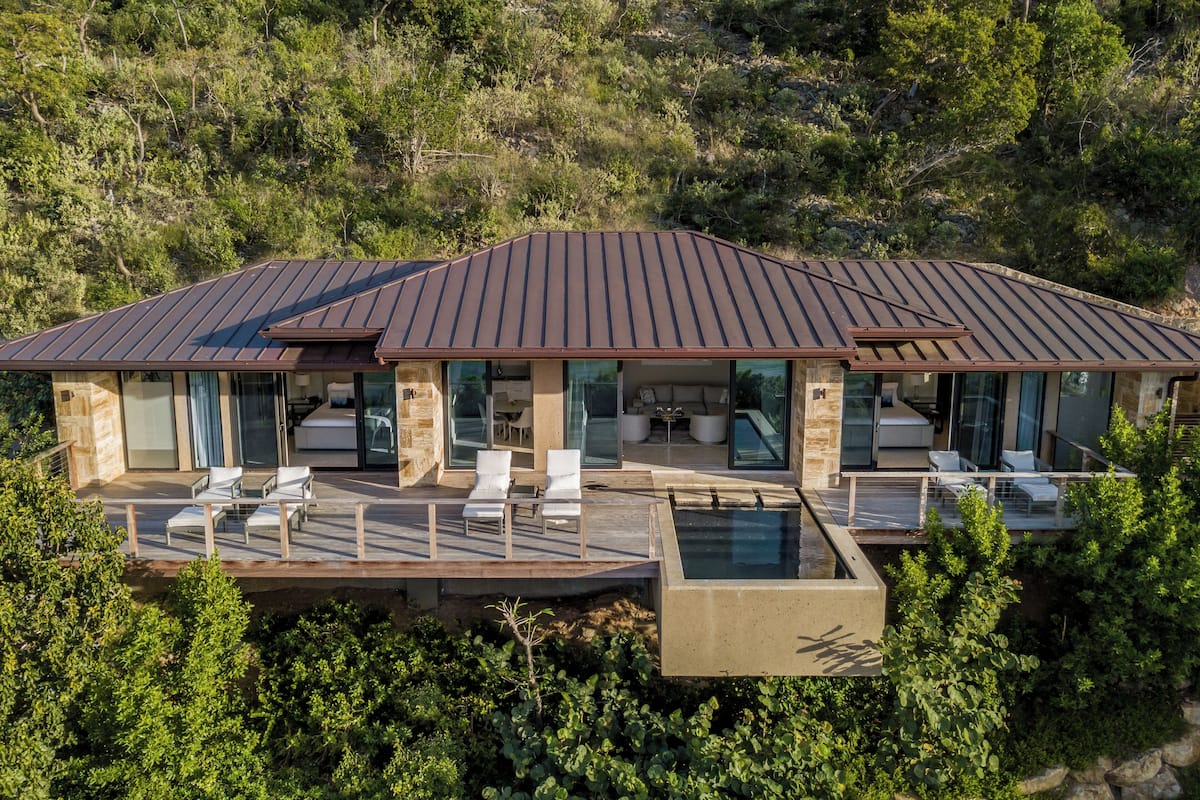 A modern house with a large deck, outdoor seating, and a swimming pool.