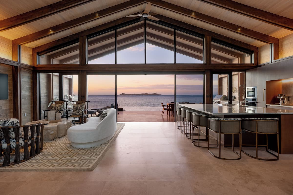 A spacious living area with a large view of the ocean, a modern kitchen, and a dining area with bar stools.