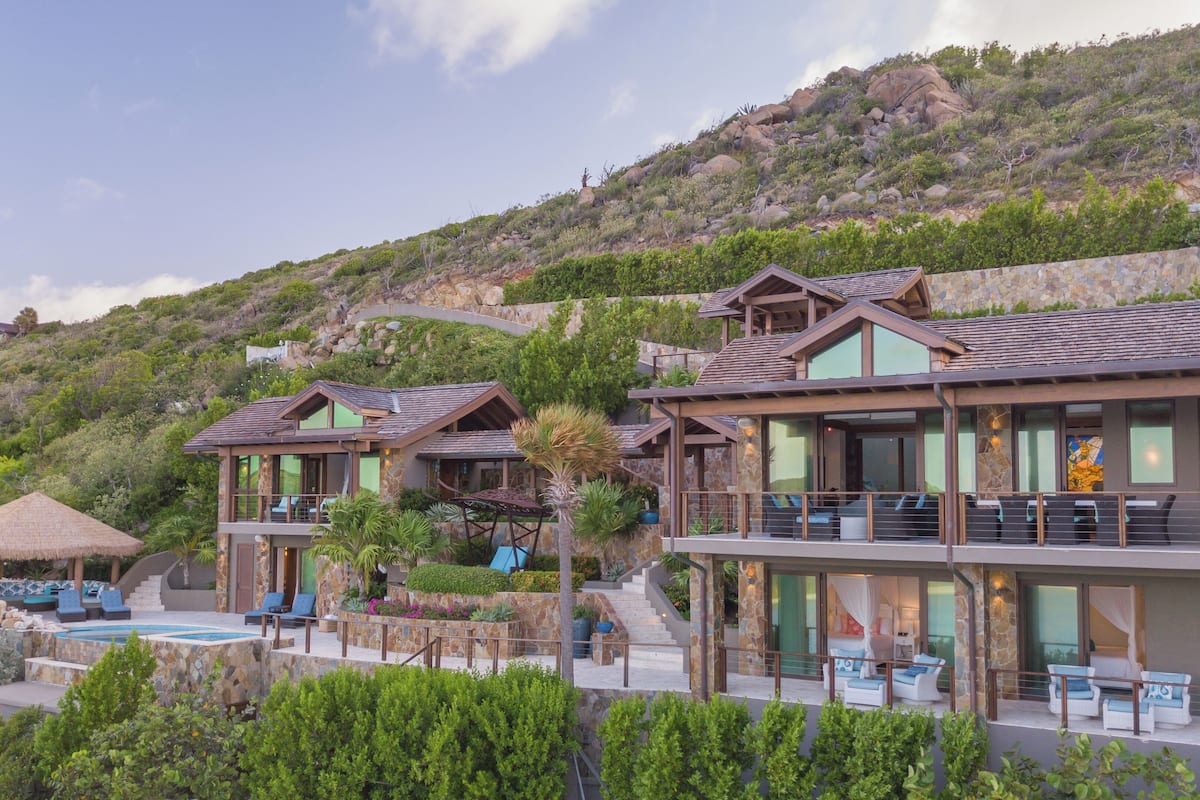 A modern resort with multiple guest rooms, a pool, and a mountainous backdrop.