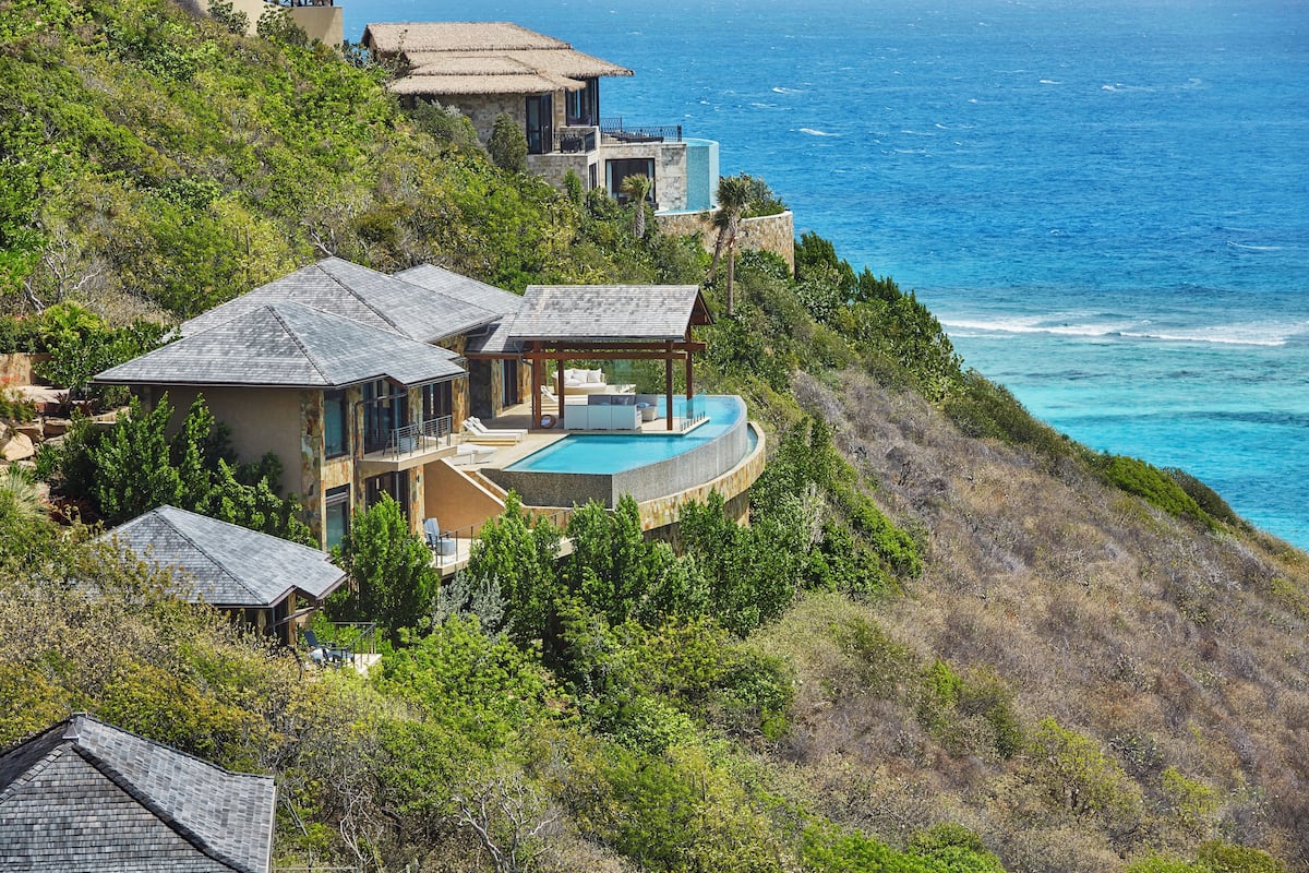 A coastal property with a swimming pool, multiple buildings, and a view of the ocean.