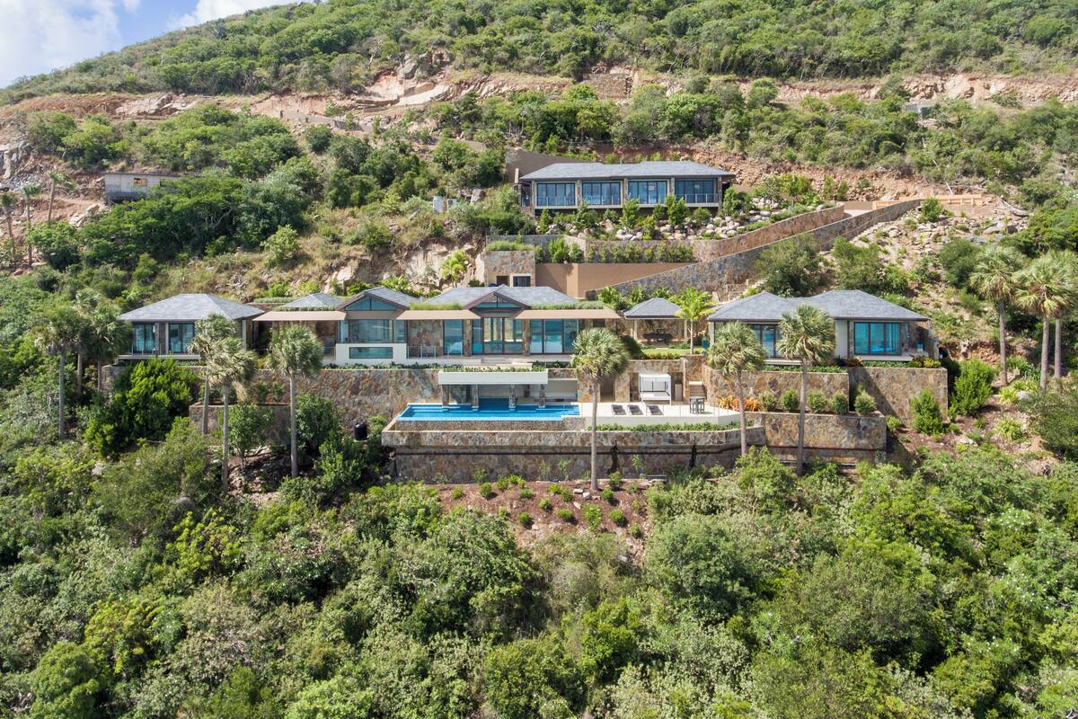 A hillside property with multiple modern villas, a swimming pool, and lush greenery.