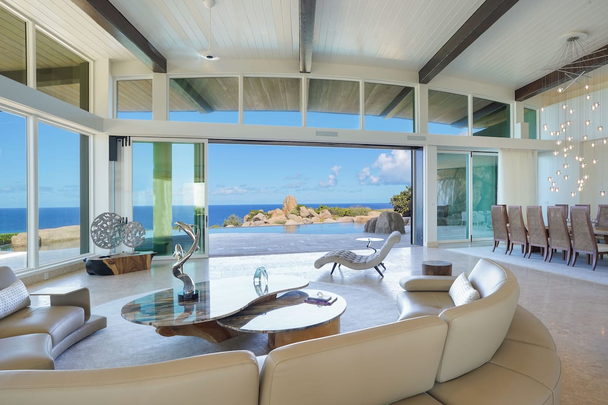 A spacious living area with a large glass door leading to a balcony overlooking the ocean.