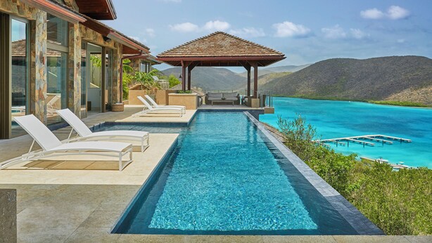 A swimming pool with lounge chairs and a gazebo overlooking a turquoise sea and mountains. - Oil Nut Bay (Virgin Gorda)