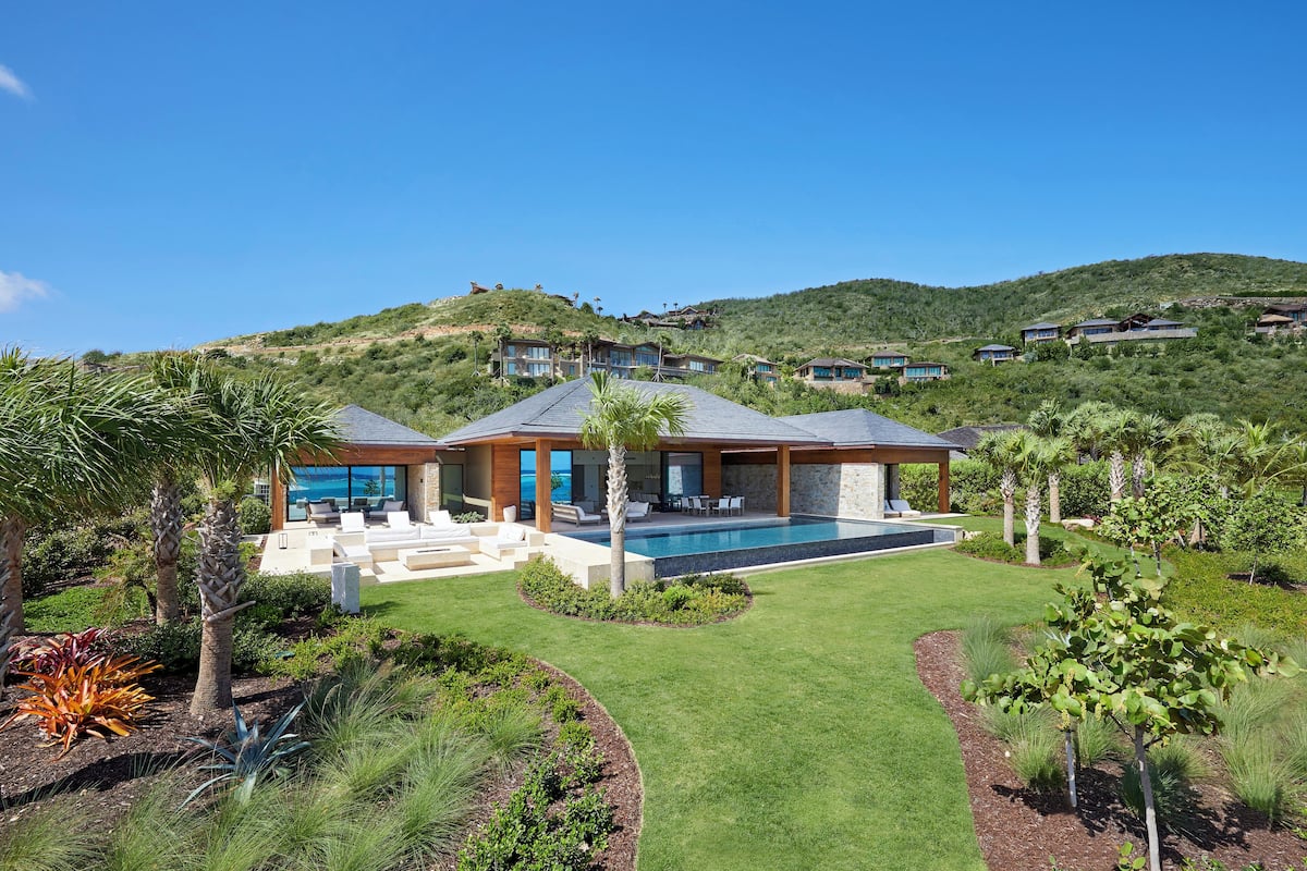 A modern house with a swimming pool, surrounded by well-maintained gardens and palm trees.