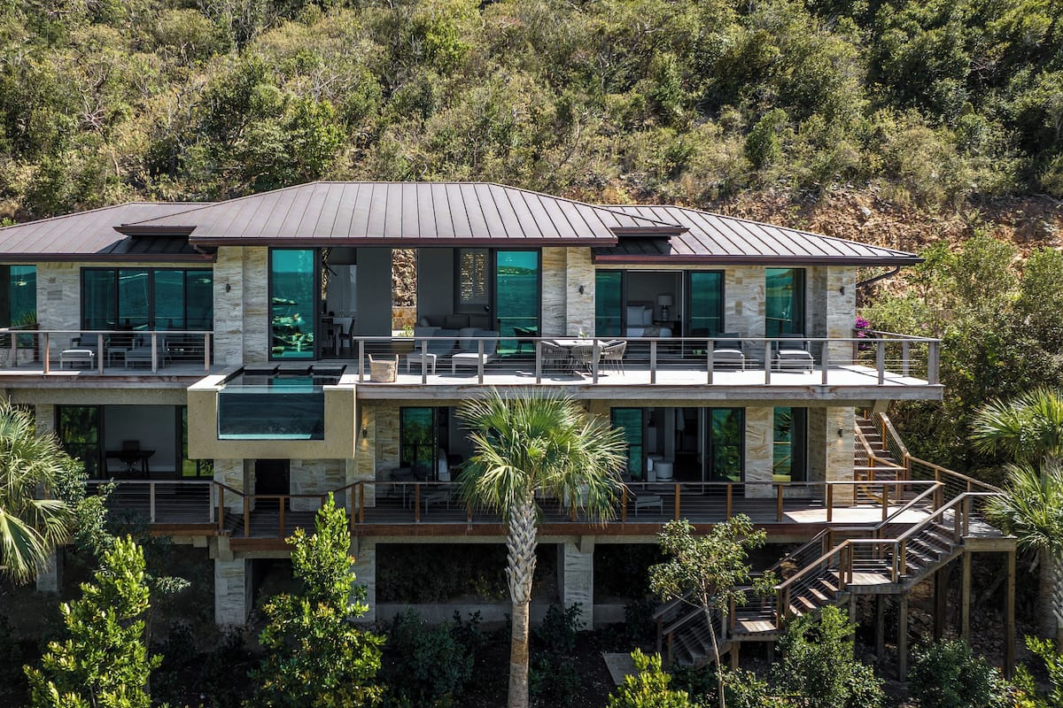 A modern two-story house with a stone facade, large windows, and a balcony.