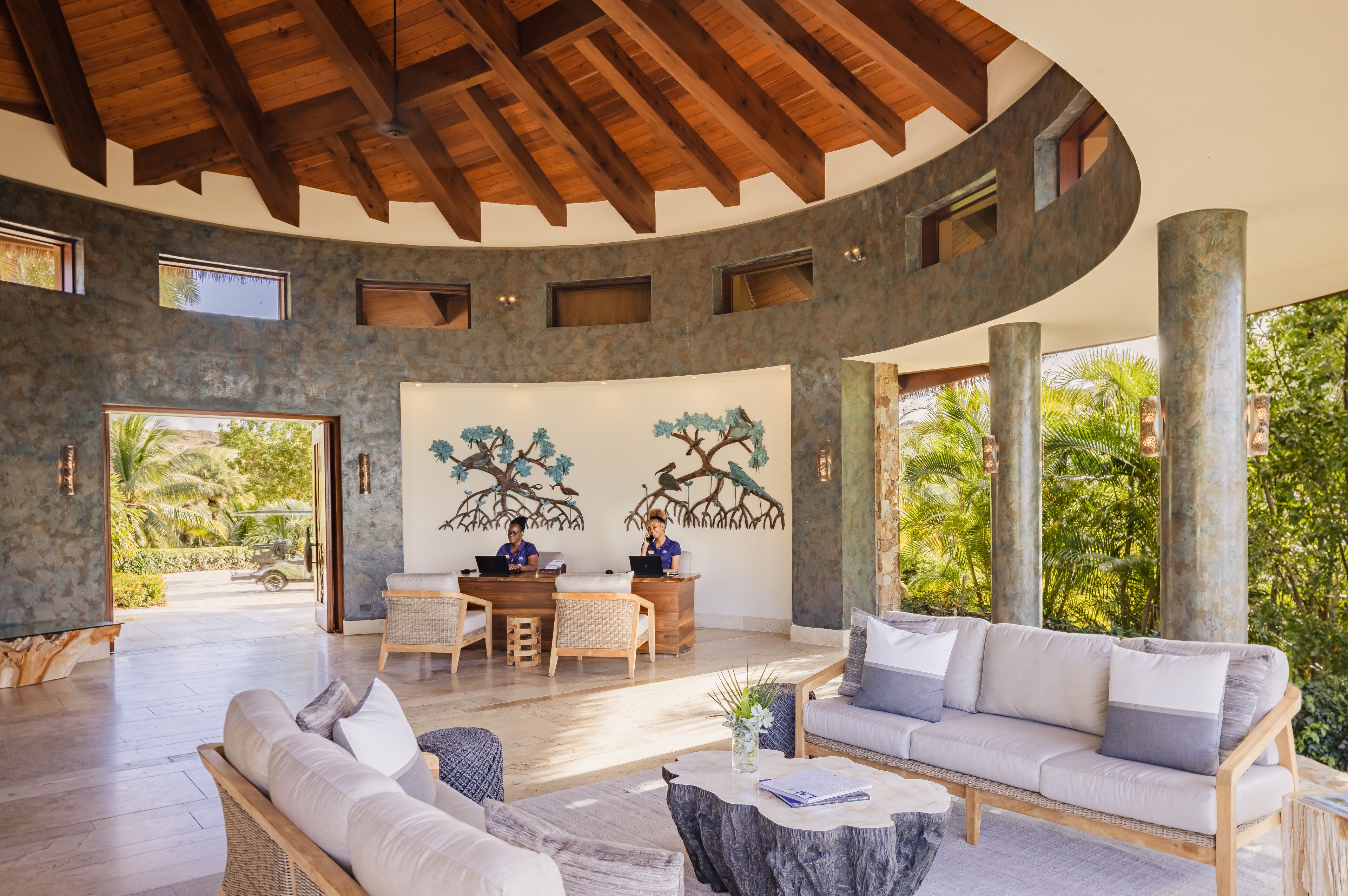 A spacious indoor area with a curved ceiling, a reception desk, two sofas, and a dining table.